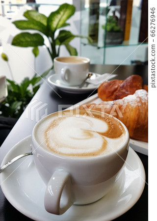 Cup of cappucino with croissant on black table in 66276946