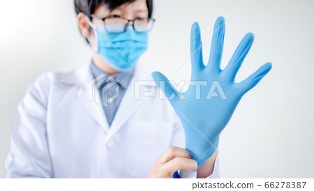 Doctor putting disposable latex gloves on hand Doctor putting disposable latex gloves on hand 66278387