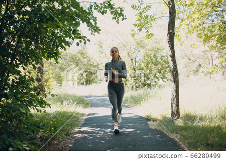 Running girl in city park. Young woman runner outdoor jogging. 66280499