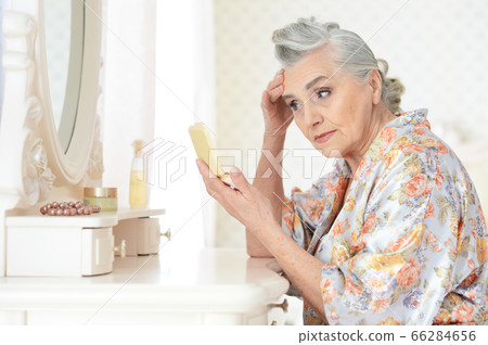 Happy senior woman sitting near dressing table Happy senior woman sitting near dressing table 66284656