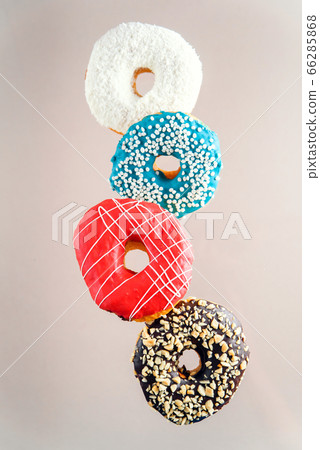 Multicolored decorated doughnuts in motion falling on brown background. Sweet donuts flying in motion. 66285868