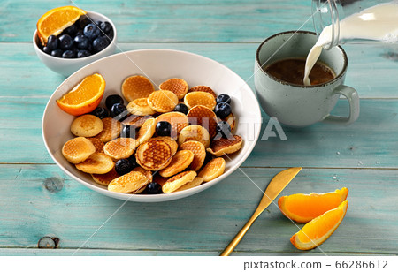 Close up of mini pancakes in white plate on light green blue background 66286612