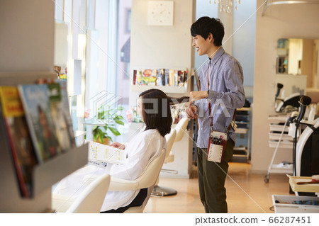 Hairdresser Young male hairdresser doing a cut Hairdresser Young male hairdresser doing a cut 66287451