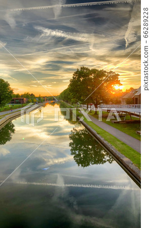 Dramatic sunset over a body of water surrounded by trees Dramatic sunset over a body of water surrounded by trees 66289228