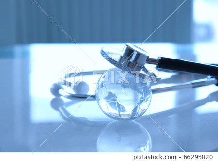 Closeup glass globe placing over stethoscope, blue toned. Concept for global healthcare and medical research Closeup glass globe placing over stethoscope, blue toned. Concept for global healthcare and medical research 66293020