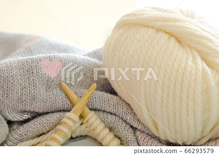 Closeup wooden knitting needles and yarn ball on gray knitted fabric and pink hearts, for Valentine's day and love concept 66293579