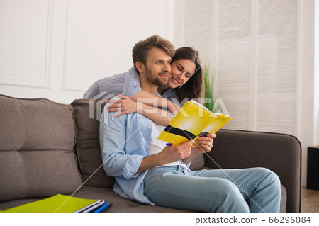Young man studying before exam, his wife hugging him and smiling 66296084