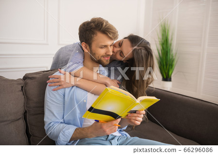 Young man studying before exam, his wife kissing him 66296086