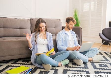Young couple sitting on the floor studying together and looking involved 66296111