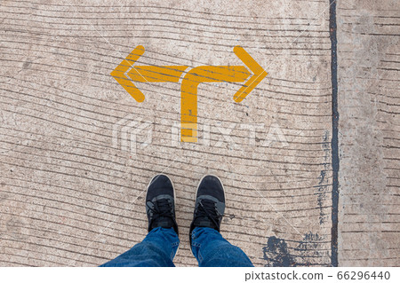 Go left or right. a man standing on the road 66296440