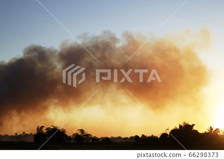 Many black smoke rise in the sky at sunset. The Many black smoke rise in the sky at sunset. The 66298373