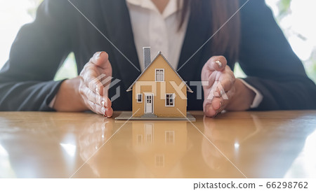Agent hand protecting house model that shows to customers to get house insurance. 66298762