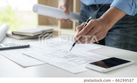 Architect or Engineer working in office with engineering tools, blueprint and building model. Architect or Engineer working in office with engineering tools, blueprint and building model. 66299587