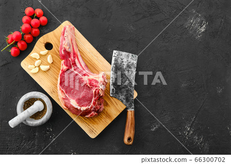 Top view of beef ribeye steak bone-in with spice on black background 66300702