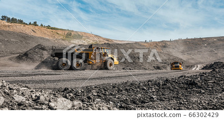 Large quarry dump truck. Loading the rock in dumper. Loading coal into body truck. Production useful minerals. Mining truck mining machinery, to transport coal from open-pit excavator work 66302429
