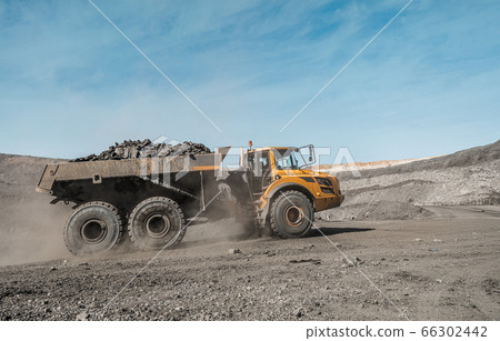 Large quarry dump truck. Loading the rock in dumper. Loading coal into body truck. Production useful minerals. Mining truck mining machinery, to transport coal from open-pit excavator work 66302442