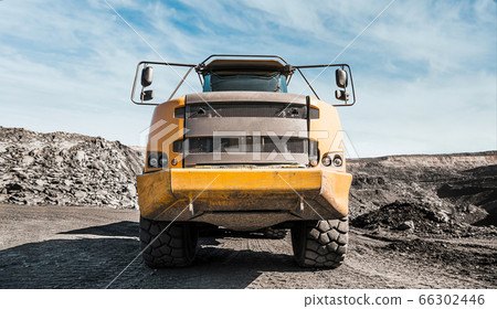 Large quarry dump truck. Loading the rock in dumper. Loading coal into body truck. Production useful minerals. Mining truck mining machinery, to transport coal from open-pit excavator work Large quarry dump truck. Loading the rock in dumper. Loading coal into body truck. Production useful minerals. Mining truck mining machinery, to transport coal from open-pit excavator work 66302446