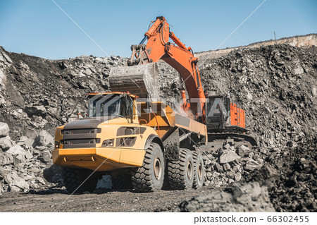 Large quarry dump truck. Loading the rock in dumper. Loading coal into body truck. Production useful minerals. Mining truck mining machinery, to transport coal from open-pit excavator work 66302455