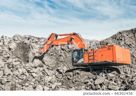Large quarry dump truck. Loading the rock in dumper. Loading coal into body truck. Production useful minerals. Mining truck mining machinery, to transport coal from open-pit excavator work Large quarry dump truck. Loading the rock in dumper. Loading coal into body truck. Production useful minerals. Mining truck mining machinery, to transport coal from open-pit excavator work 66302456