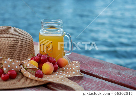 Glass of tropical exotic multifruit juice and fruits at the pier. Tropical beach picnic. Glass of tropical exotic multifruit juice and fruits at the pier. Tropical beach picnic. 66302815