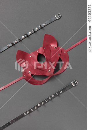 Red leather cat BDSM mask and stud collars on a black background. Red leather cat BDSM mask and stud collars on a black background. 66303271