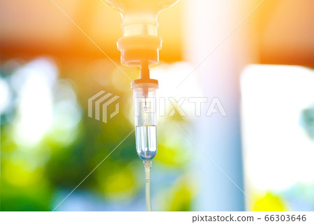 Chemotherapy drug medical holding hypodermic syringe needle injection iv bag fluid intravenous drop saline drip hospital room concept treatment  palliative care.selective focus.blue light background, 66303646