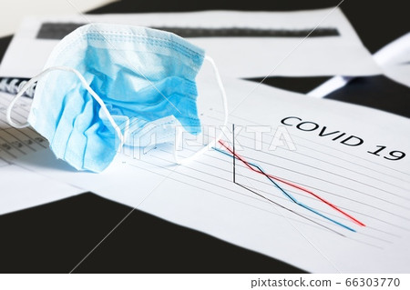 End of pandemic coronavirus and isolation. Used crumpled medical mask on chart for reducing the incidence of morbidity and mortality. Selective focus End of pandemic coronavirus and isolation. Used crumpled medical mask on chart for reducing the incidence of morbidity and mortality. Selective focus 66303770