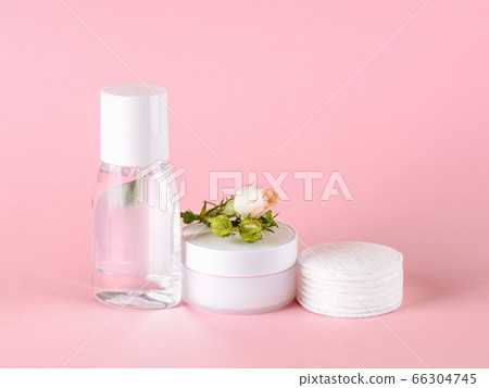 Skin tonic lotion or micellar water, facial cream, cotton pads and small rose on a pastel pink. Skin tonic lotion or micellar water, facial cream, cotton pads and small rose on a pastel pink. 66304745