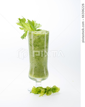 celery leaves and a glass of smoothies on a white celery leaves and a glass of smoothies on a white 66306226