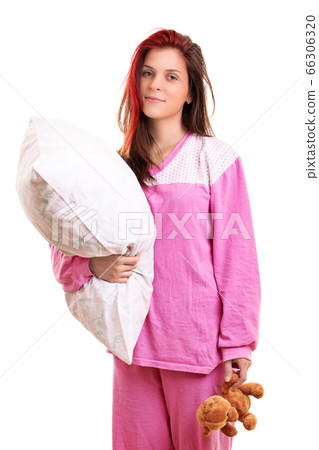 Young girl in pajamas holding a pillow and a teddy Young girl in pajamas holding a pillow and a teddy 66306320