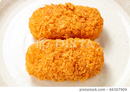 Two bale-shaped cream croquettes placed on a plate. 66307909