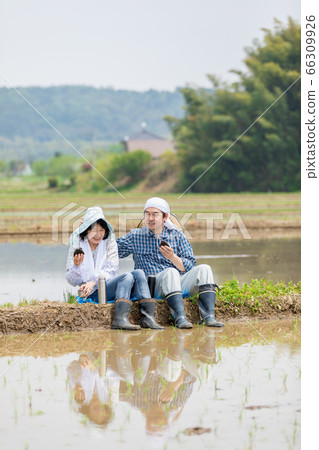 A farmer's couple having lunch on the road between rice paddies 66309926
