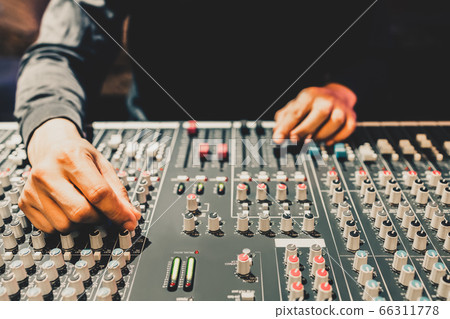 male producer, dj, sound engineer hands adjusting knob on audio mixing console 66311778