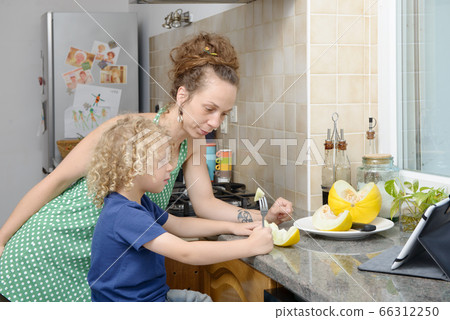 child and his mother with melon in kitchen 66312250