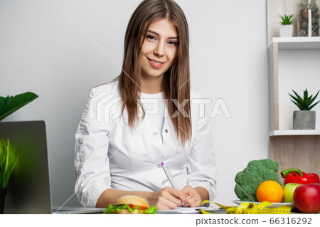 Female nutritionist with fruits working at her desk 66316292