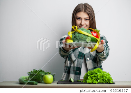 Young pretty woman adheres to diet and holds a plate of vegetables 66316337