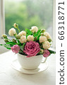 A bouquet of white roses in a cup on a white table opposite the window 66318771
