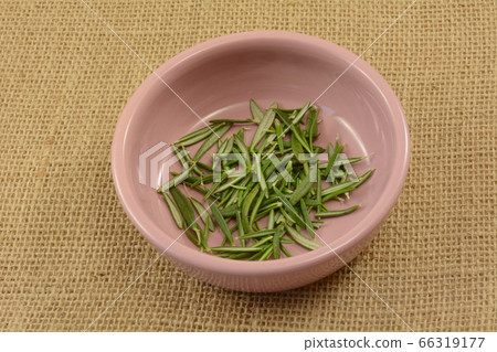 fresh green rosemary herb leaves in small pink condiment bowl on burlap fresh green rosemary herb leaves in small pink condiment bowl on burlap 66319177