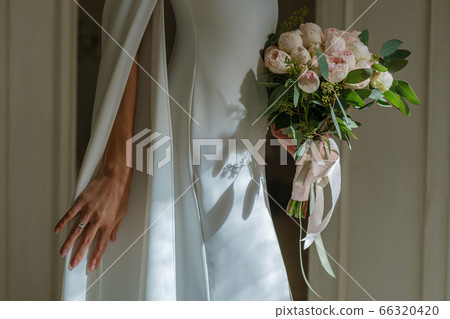 Closeup shot of bridal hands holding bouquet of peonies Closeup shot of bridal hands holding bouquet of peonies 66320420