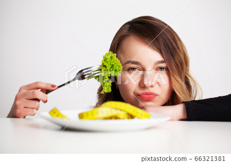 Young woman in a bright room eats lettuce for weight loss 66321381