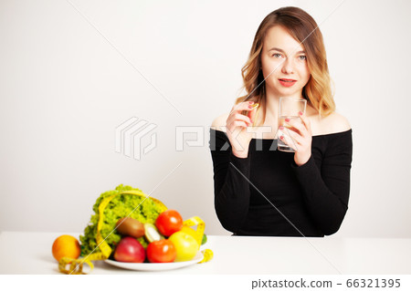 Young woman holding a glass of water and a pill for weight loss Young woman holding a glass of water and a pill for weight loss 66321395