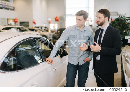 Young happy man preparing to buy new car in auto dealership. 66324340