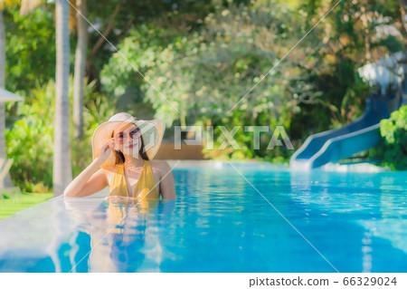 asian woman relax around outdoor swimming pool in hotel resort with palm tree at sunset or sunrise asian woman relax around outdoor swimming pool in hotel resort with palm tree at sunset or sunrise 66329024