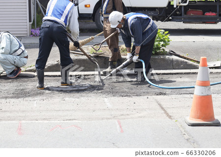 Worker cutting through asphalt on the road Worker cutting through asphalt on the road 66330206