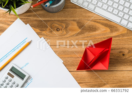 Businessman workspace at desk with red paper ship 66331792
