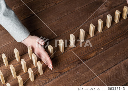Businesswoman protecting dominoes from falling Businesswoman protecting dominoes from falling 66332143