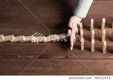 Businesswoman protecting dominoes from falling 66332419