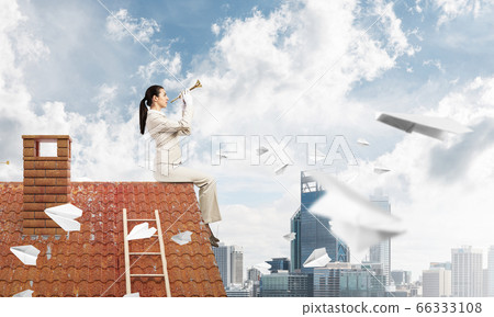 Young woman playing trumpet and sitting on roof Young woman playing trumpet and sitting on roof 66333108