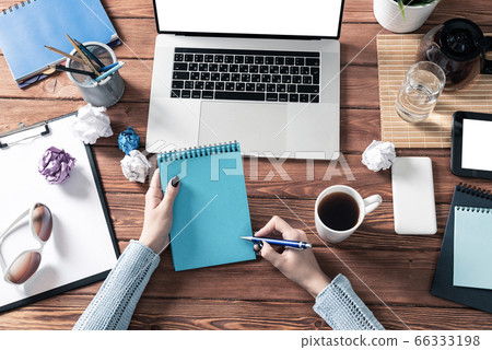 Woman writing in notebook with pen at desk 66333198