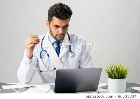 Serious arab practitioner working at computer 66333334